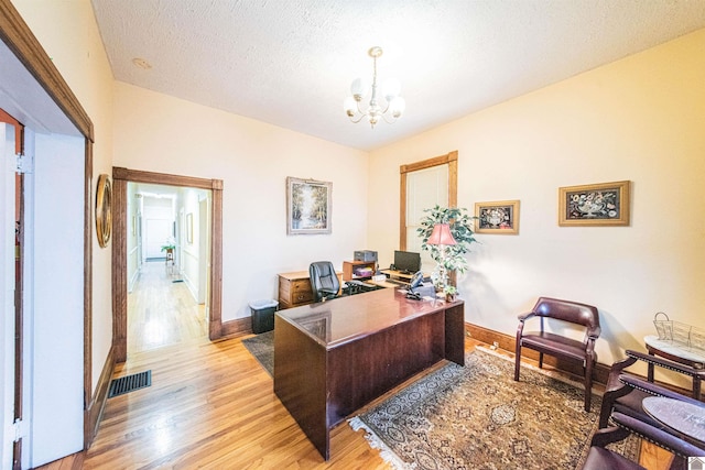 office space featuring a textured ceiling, a chandelier, and light hardwood / wood-style flooring