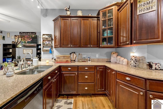 kitchen with sink, stainless steel dishwasher, light stone counters, and light hardwood / wood-style flooring