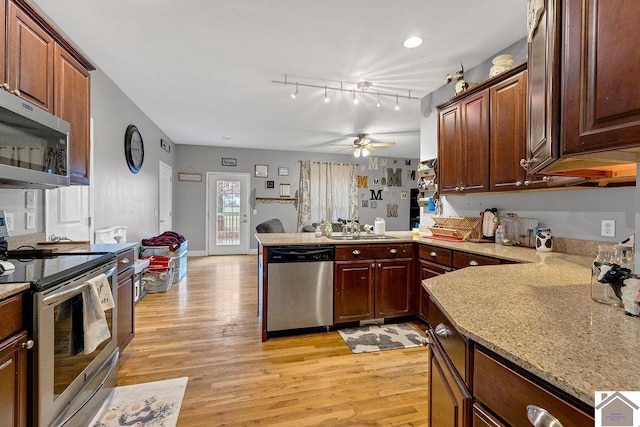 kitchen featuring sink, ceiling fan, kitchen peninsula, stainless steel appliances, and light wood-type flooring