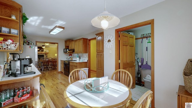 dining space with ceiling fan, a brick fireplace, and light hardwood / wood-style floors