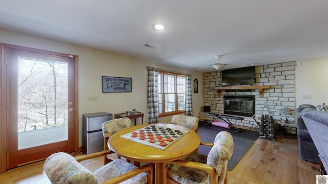 dining room featuring ceiling fan, a fireplace, and light hardwood / wood-style floors