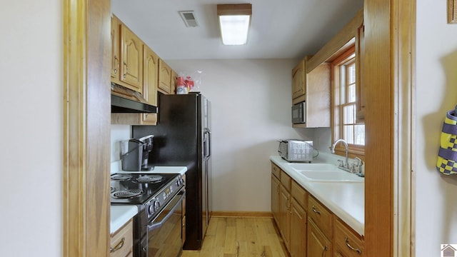 kitchen with sink, black appliances, and light hardwood / wood-style floors