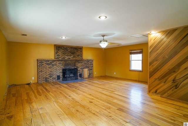 unfurnished living room featuring ceiling fan, light hardwood / wood-style floors, and a brick fireplace