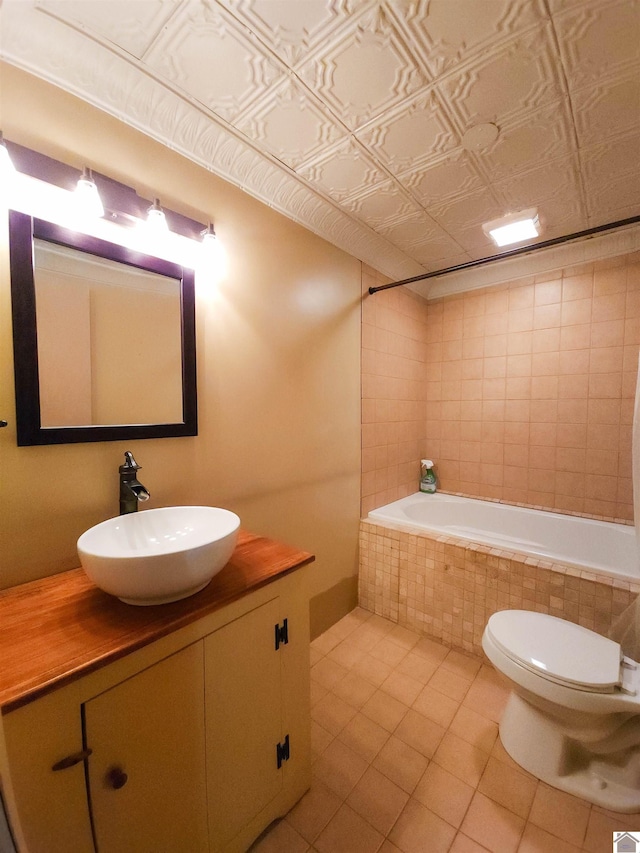 bathroom featuring vanity, a relaxing tiled tub, tile patterned floors, and toilet