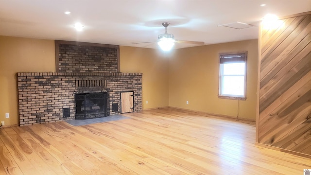 unfurnished living room with ceiling fan, a fireplace, and light wood-type flooring