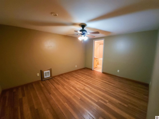 unfurnished bedroom with heating unit, hardwood / wood-style flooring, ensuite bath, and ceiling fan