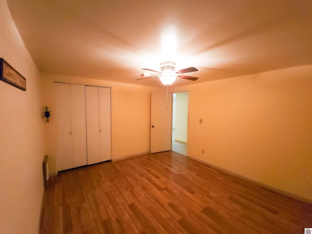 unfurnished bedroom with wood-type flooring, a closet, and ceiling fan