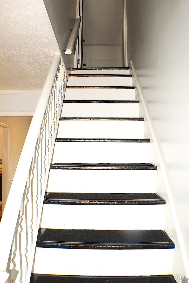 stairway featuring a textured ceiling