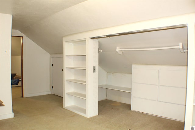 spacious closet featuring vaulted ceiling and light carpet