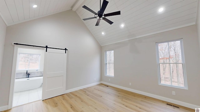 empty room featuring ceiling fan, beam ceiling, high vaulted ceiling, light hardwood / wood-style floors, and a barn door