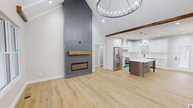 living room featuring beamed ceiling, a large fireplace, sink, light wood-type flooring, and an inviting chandelier