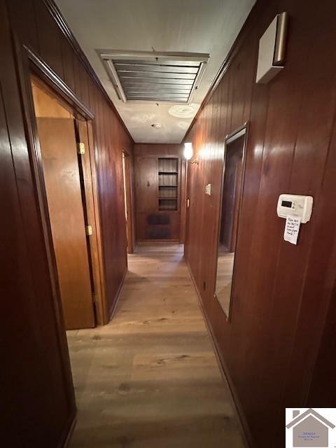 corridor featuring light hardwood / wood-style flooring and wood walls