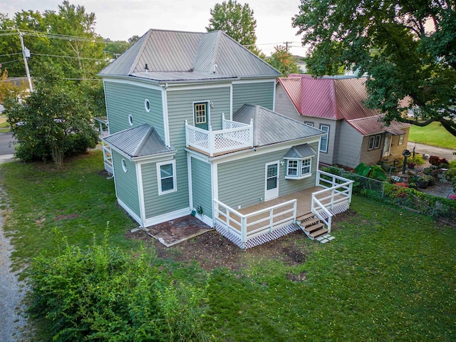 back of house with a wooden deck, a balcony, and a yard