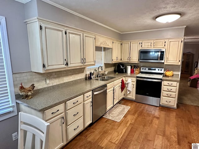 kitchen featuring sink, crown molding, appliances with stainless steel finishes, light hardwood / wood-style floors, and decorative backsplash