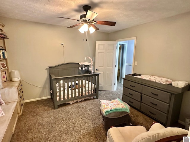 carpeted bedroom featuring a crib, ceiling fan, and a textured ceiling