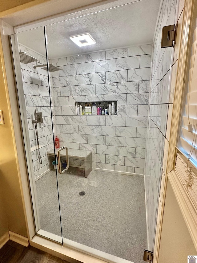 bathroom with a shower with shower door and a textured ceiling