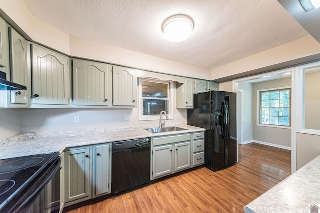 kitchen with sink, light hardwood / wood-style flooring, black appliances, and a textured ceiling