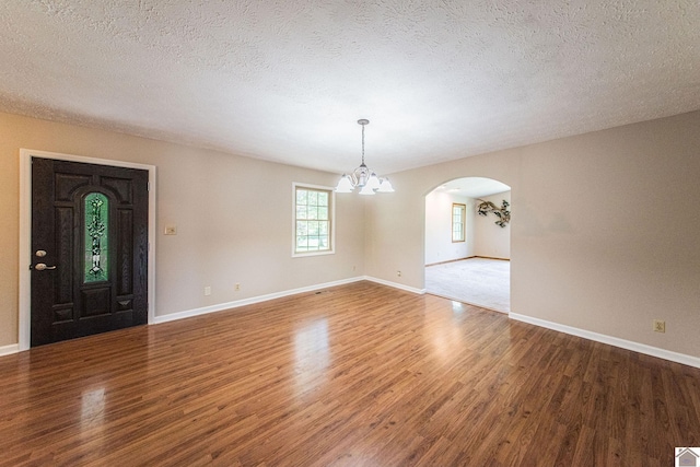 foyer entrance with a textured ceiling, wood-type flooring, and a chandelier