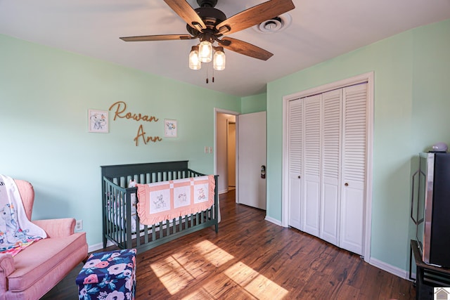 bedroom with dark wood-type flooring, ceiling fan, and a closet