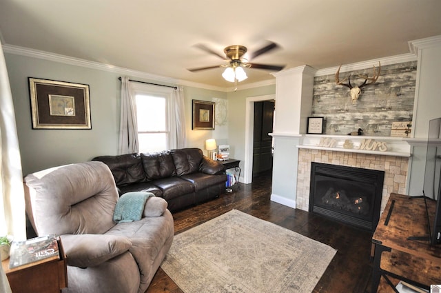 living room with a tile fireplace, dark wood-type flooring, ceiling fan, and crown molding