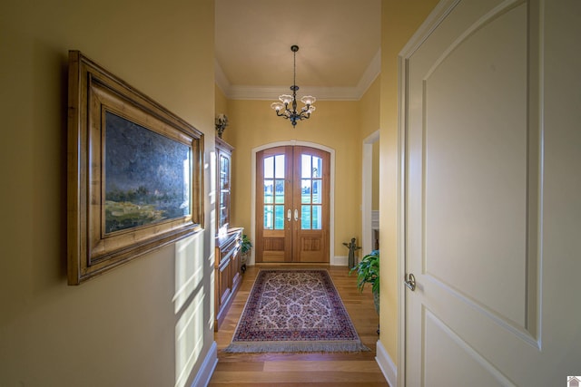 doorway to outside with a notable chandelier, crown molding, french doors, and light wood-type flooring