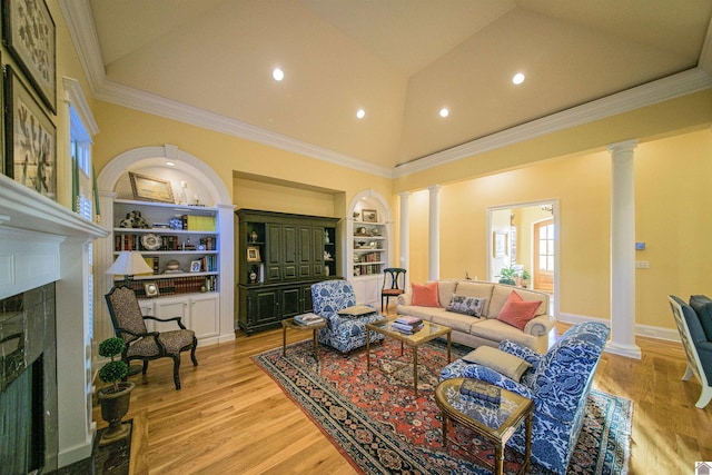 living room with decorative columns, ornamental molding, built in shelves, and light hardwood / wood-style flooring