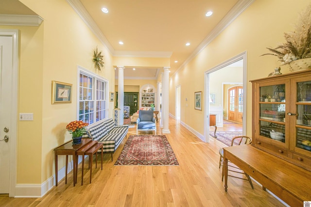 hall with crown molding, light hardwood / wood-style flooring, and decorative columns