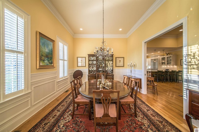 dining space featuring an inviting chandelier, hardwood / wood-style floors, crown molding, and a wealth of natural light