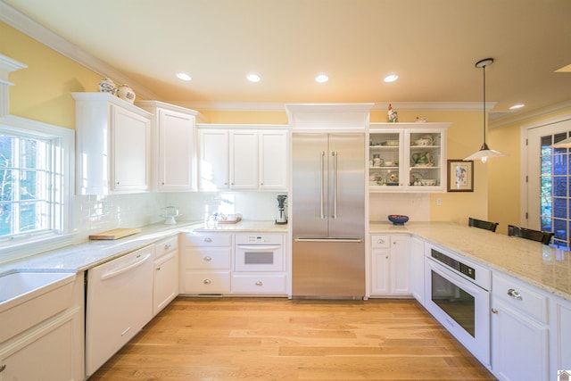 kitchen with crown molding, white appliances, light hardwood / wood-style flooring, white cabinets, and decorative light fixtures