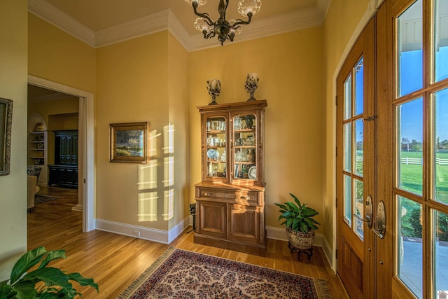 doorway featuring crown molding, a chandelier, and light wood-type flooring