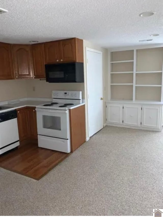 kitchen featuring white appliances, light carpet, and a textured ceiling