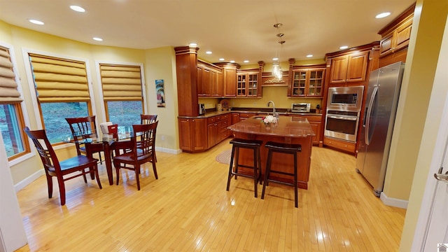 kitchen with a center island with sink, sink, a breakfast bar, decorative light fixtures, and stainless steel appliances