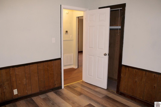 unfurnished bedroom featuring dark hardwood / wood-style flooring, a closet, and wood walls