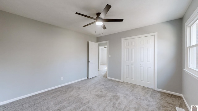 unfurnished bedroom featuring light colored carpet, ceiling fan, and a closet