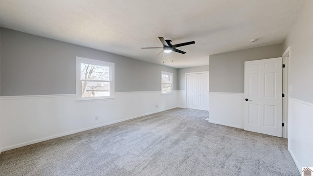 unfurnished bedroom featuring light colored carpet, a closet, and ceiling fan