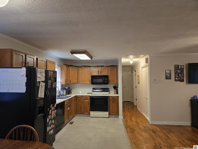 kitchen featuring sink, light hardwood / wood-style flooring, ornamental molding, black appliances, and a textured ceiling