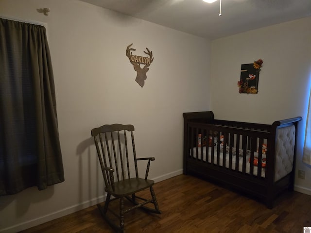 bedroom with a crib and dark hardwood / wood-style flooring