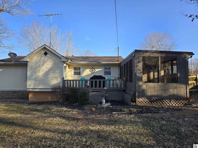 rear view of house featuring a wooden deck, a yard, and a sunroom