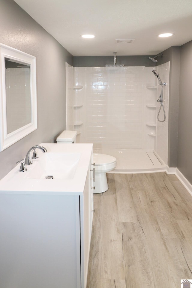 bathroom featuring walk in shower, hardwood / wood-style floors, vanity, and toilet