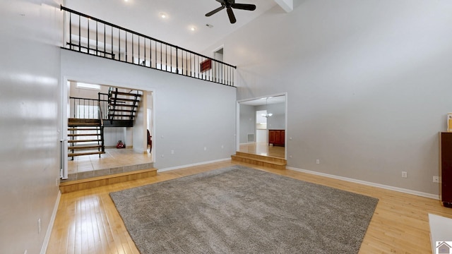 unfurnished living room featuring a high ceiling, wood-type flooring, and ceiling fan