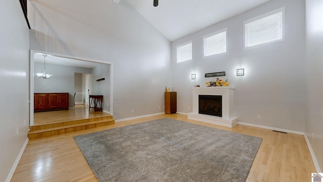 unfurnished living room featuring wood-type flooring, high vaulted ceiling, and a chandelier