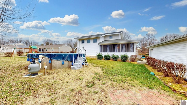 rear view of property with a yard, a covered pool, and a sunroom