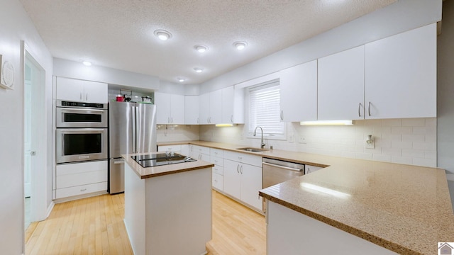 kitchen with appliances with stainless steel finishes, a center island, sink, and white cabinets