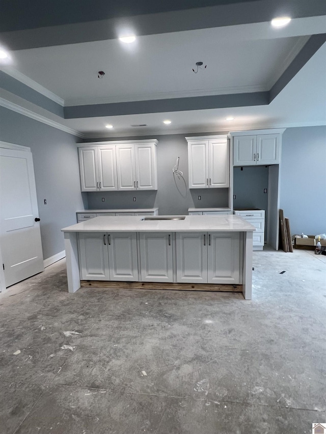 kitchen with ornamental molding, white cabinetry, a raised ceiling, and a kitchen island