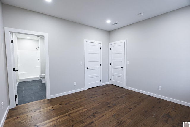 unfurnished bedroom with dark wood-type flooring and ensuite bathroom