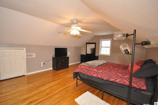 bedroom with ceiling fan, light wood-type flooring, and vaulted ceiling