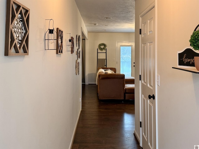 hallway with dark wood-type flooring and a textured ceiling