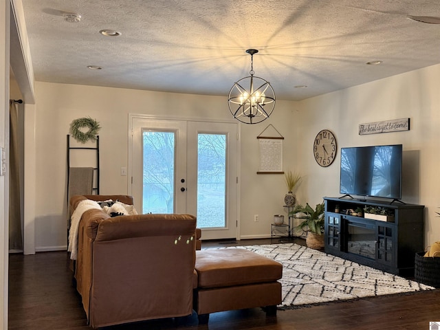 living room with dark hardwood / wood-style flooring, a chandelier, french doors, and a textured ceiling