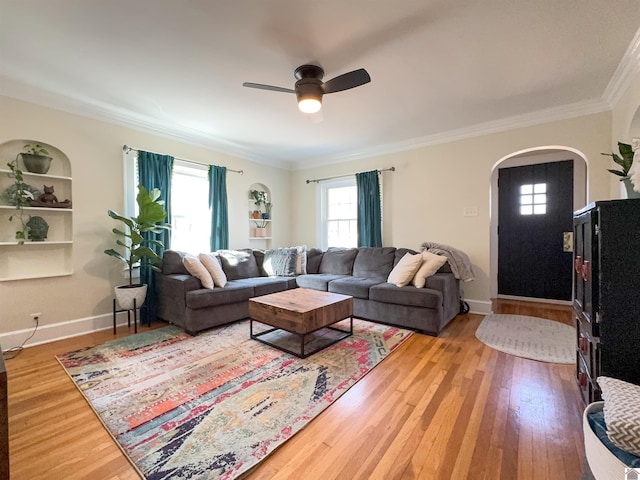 living room featuring hardwood / wood-style flooring, ceiling fan, crown molding, and built in features