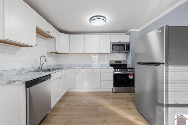 kitchen featuring light wood-type flooring, white cabinetry, stainless steel appliances, sink, and ornamental molding